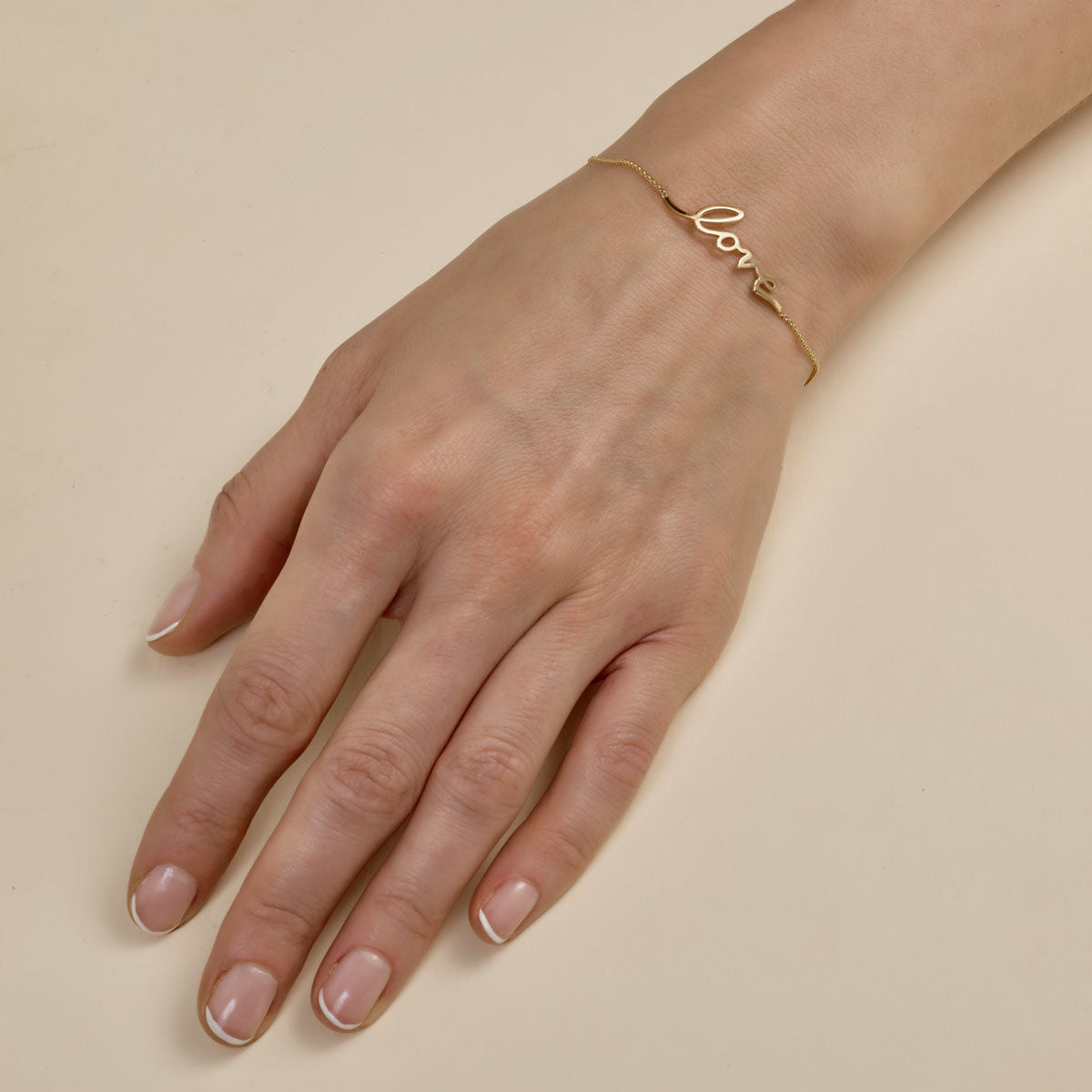 Cursive gold love script bracelet - elegant romantic jewelry on woman's wrist