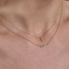 Gold diamond cross and NYC necklaces on neck - layered faith and city-inspired jewelry