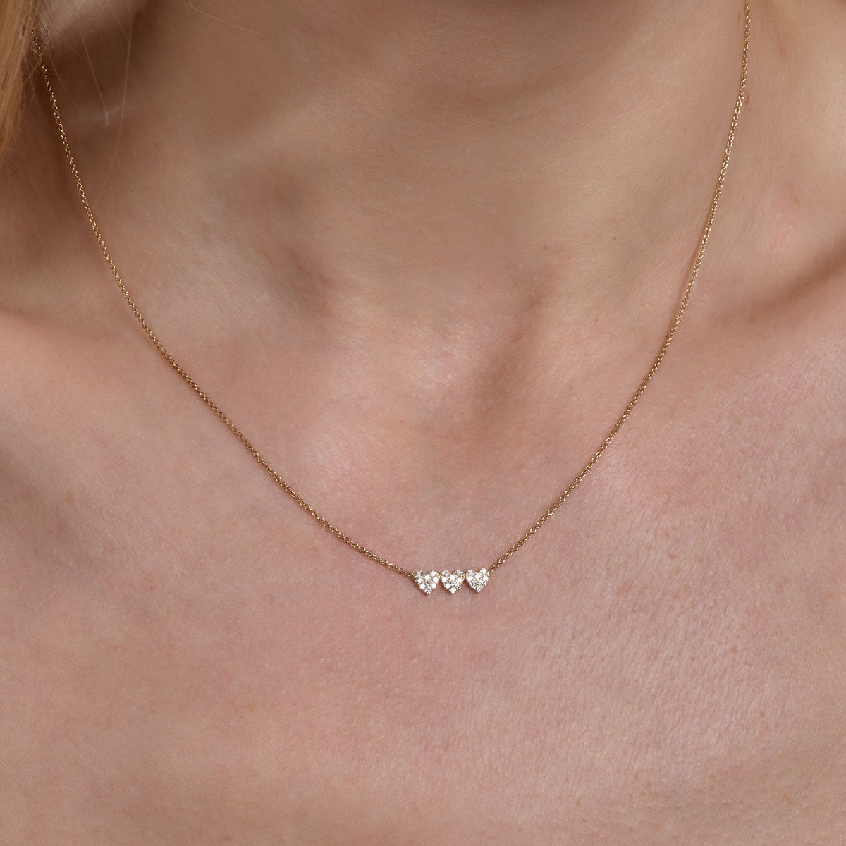 Delicate gold diamond triple heart necklace - sparkling romantic charm on woman's neck